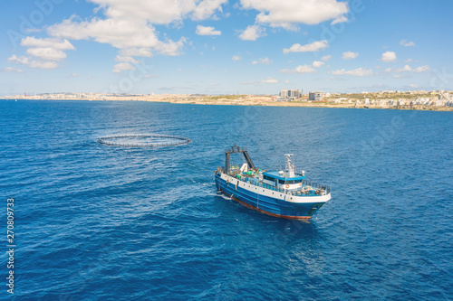 Fishing vessel boat floating in the blue sea along the coast. © aapsky