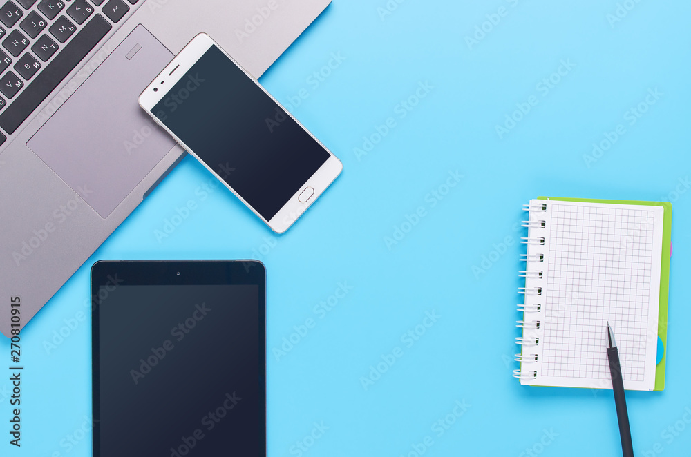 top view upon gadgets on blue background, the composition of a laptop, white headphones, phone, glass with a drink and car keys top view upon gadgets on blue background, the composition of a laptop, white headphones, phone, glass with a drink and car keys