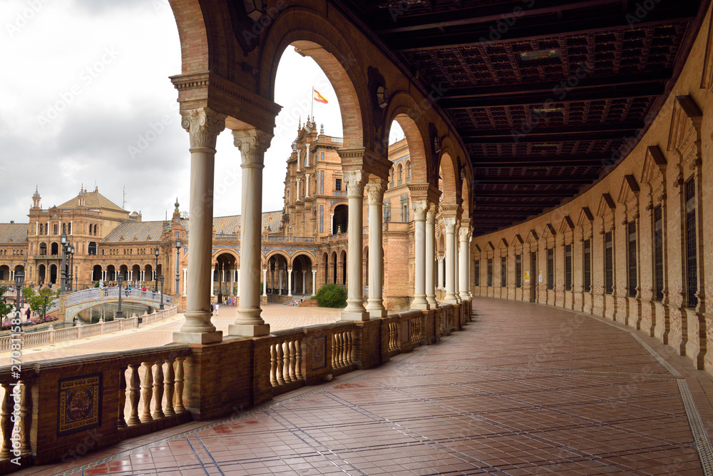 Main building with curved roofed walkway with pillars at Plaza de Espana Seville Spain