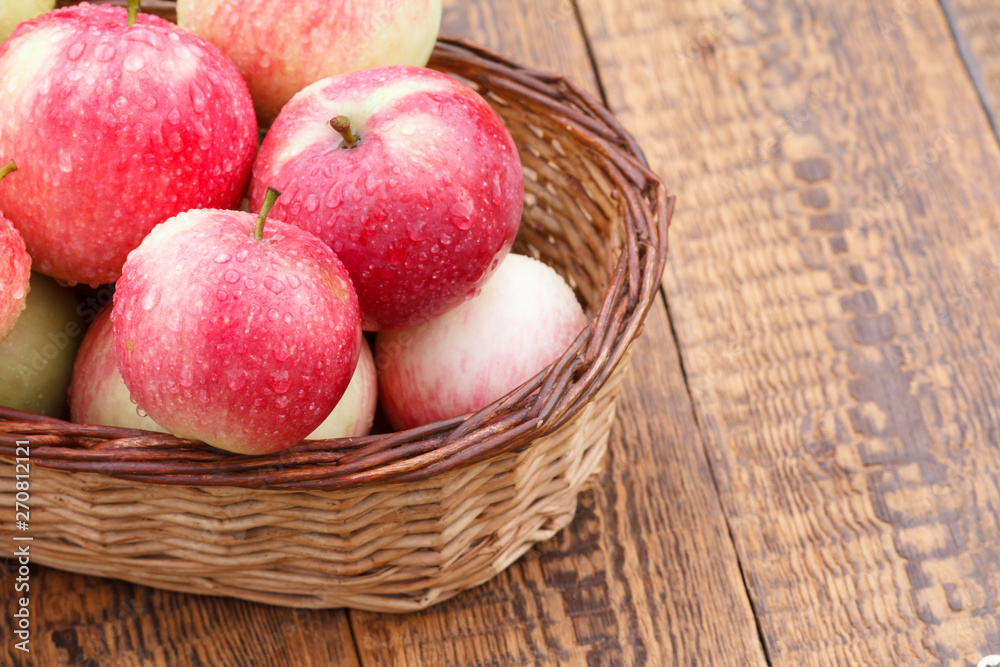 Red apples in the wicker basket on wooden boards Red apples in the wicker basket on wooden boards