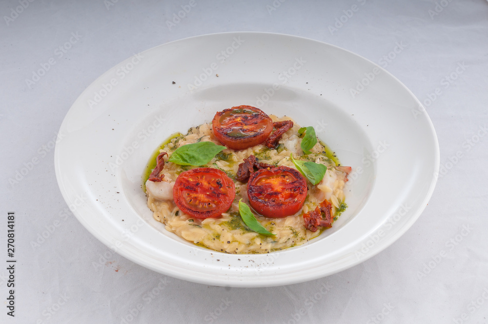 seafood risotto and dried tomatoes on a white plate on a white background seafood risotto and dried tomatoes on a white plate on a white background