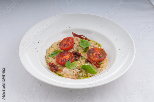 seafood risotto and dried tomatoes on a white plate on a white background