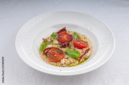 seafood risotto and dried tomatoes on a white plate on a white background