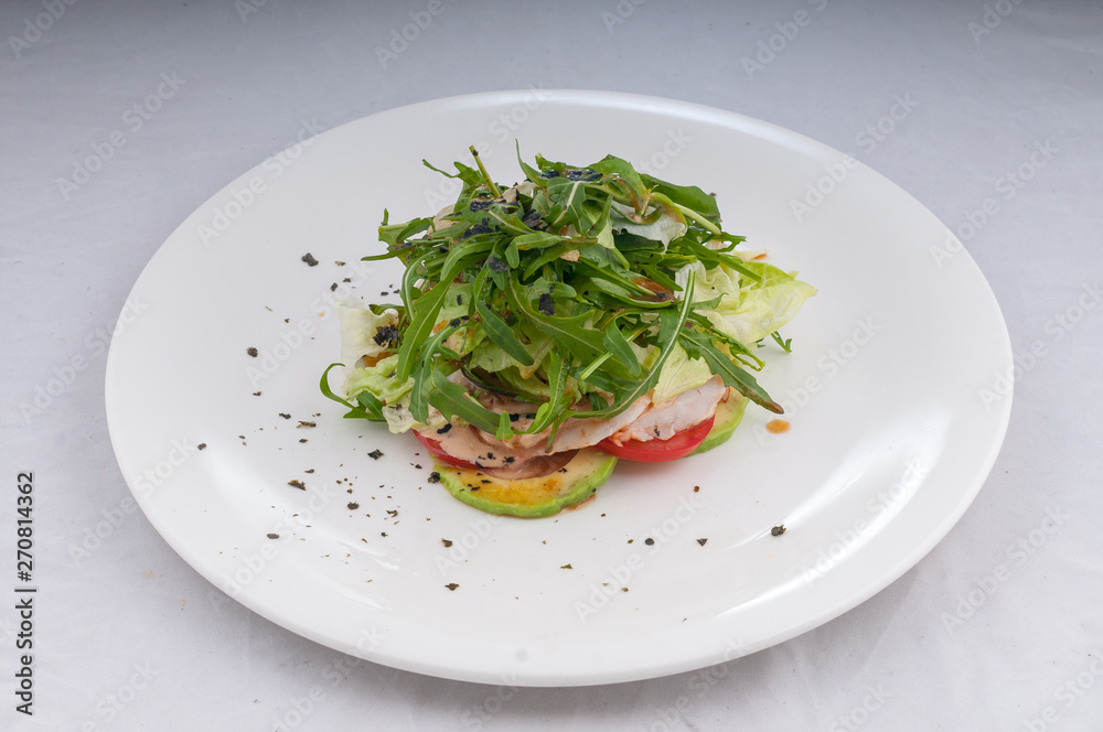salad with rucola and vegetables zucchini tomatoes on a white plate on a clean white background