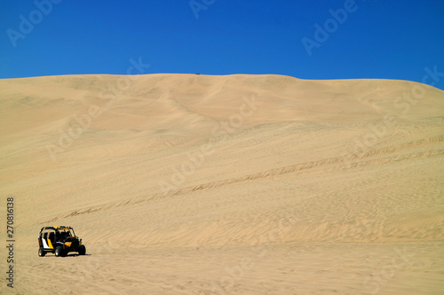 Dune buggy running up onto the sand dunes of Huacachina desert in Ica region, Peru