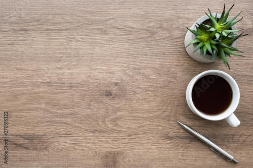 Wood office desk table with cup of coffee, pen and cactus pot. Top view with copy space, flat, lay.