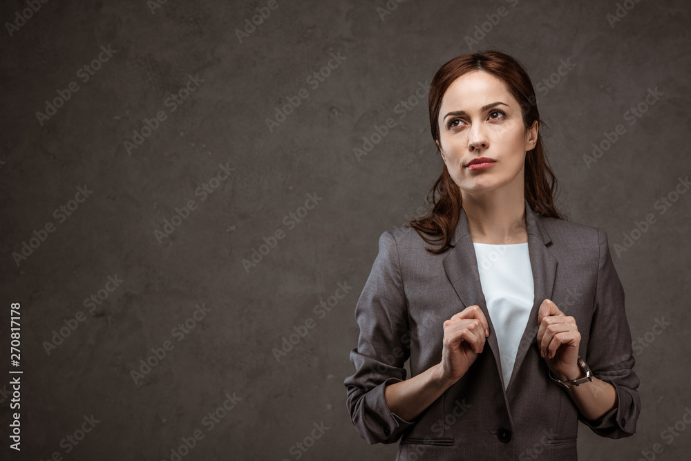 thoughtful brunette businesswoman in formal wear standing on grey thoughtful brunette businesswoman in formal wear standing on grey