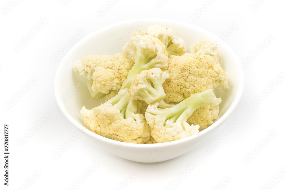 Cauliflower sliced into small pieces in a white bowl Cauliflower sliced into small pieces in a white bowl