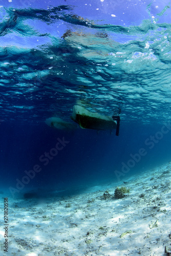 The bottom of the fishing boat view from under the water. Blue underwater background. Bali, Raja Ampat, Papua Indonesia.