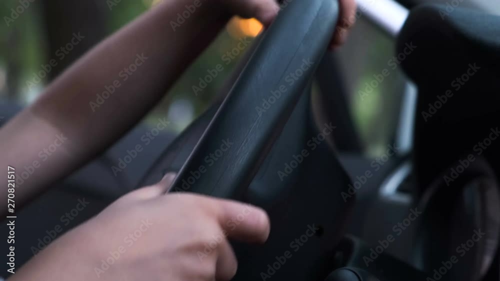 The hands of a little boy twist the wheel of a car The hands of a little boy twist the wheel of a car