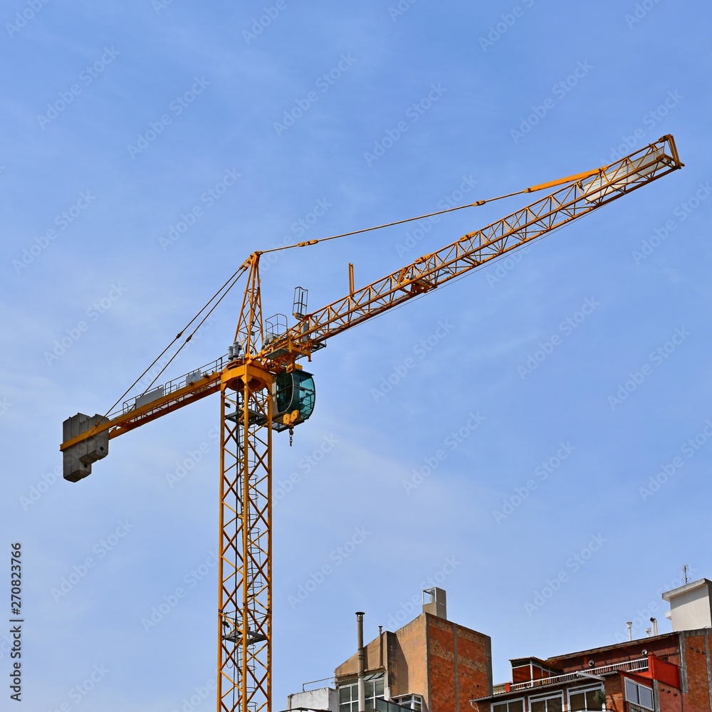 construction crane above the houses against the sky