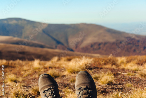 Hiker have relaxing time during an outdoor trekking in mountains. Freedom and lifestyle concept. Travel background, hiking shoes on mountain background. Autumn holidays © volurol