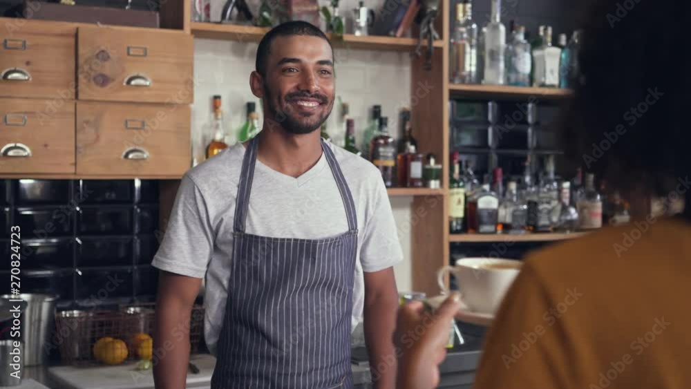 Male barista serving coffee to the customer at counter