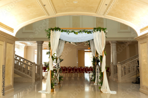 Wedding chuppah decorated with fresh flowers indoor banquet hall of wedding ceremony. Luxury wedding florist decoration artwork photo