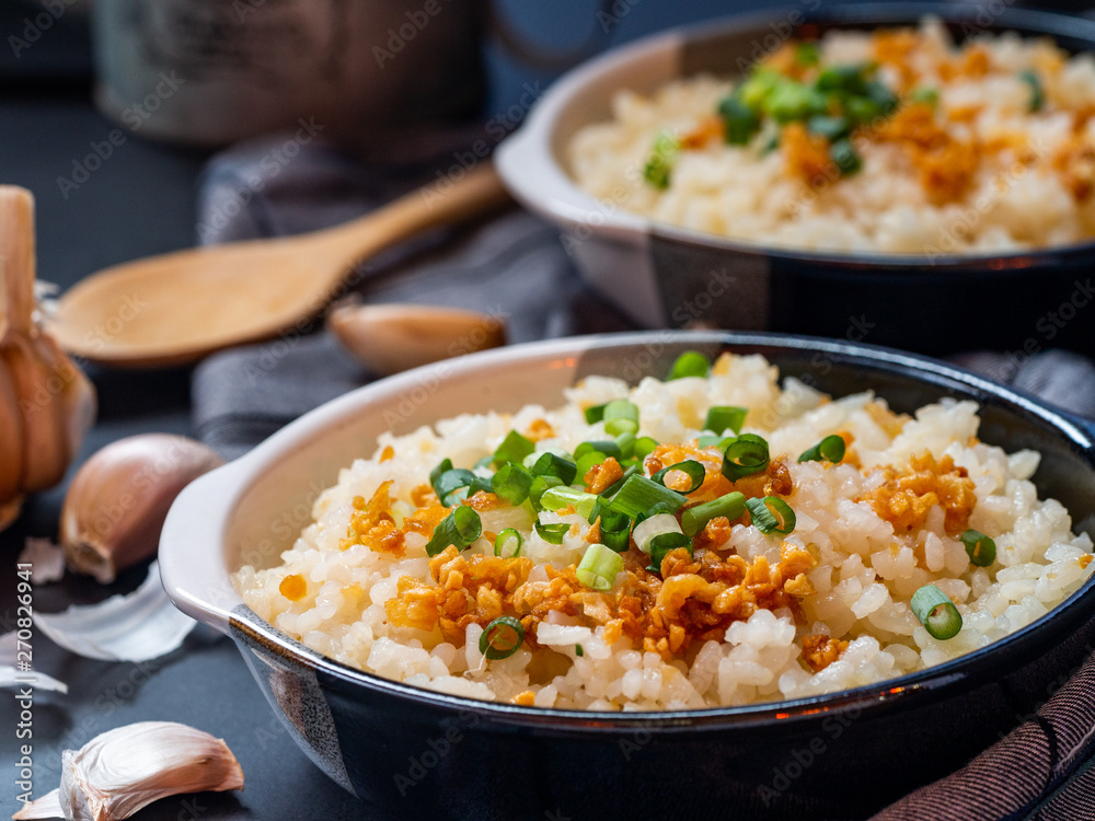 Garlic fried rice in ceramic plate with wood spoon on black background. Garlic fried rice in ceramic plate with wood spoon on black background.