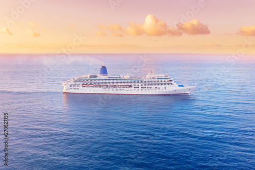 Fototapeta Naklejka Na Ścianę i Meble -  White cruise liner floats across blue sea into sunset. Concept travel. Aerial view
