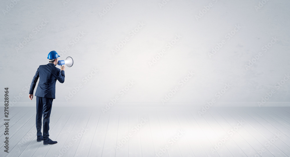 Young architect with construction helmet standing in an empty space and holding a plan
Young architect with construction helmet standing in an empty space and holding a plan