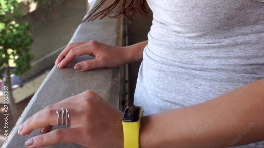 Detail on hands of anxious, waiting girl outside, looking at smartwatch. Detail on hands of anxious, waiting girl outside, looking at smartwatch.