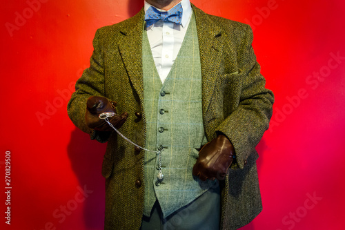 Portrait of Dapper Man in Tweed Suit and Leather Gloves Looking and Vintage Pocket Watch. Classic English Gentleman.