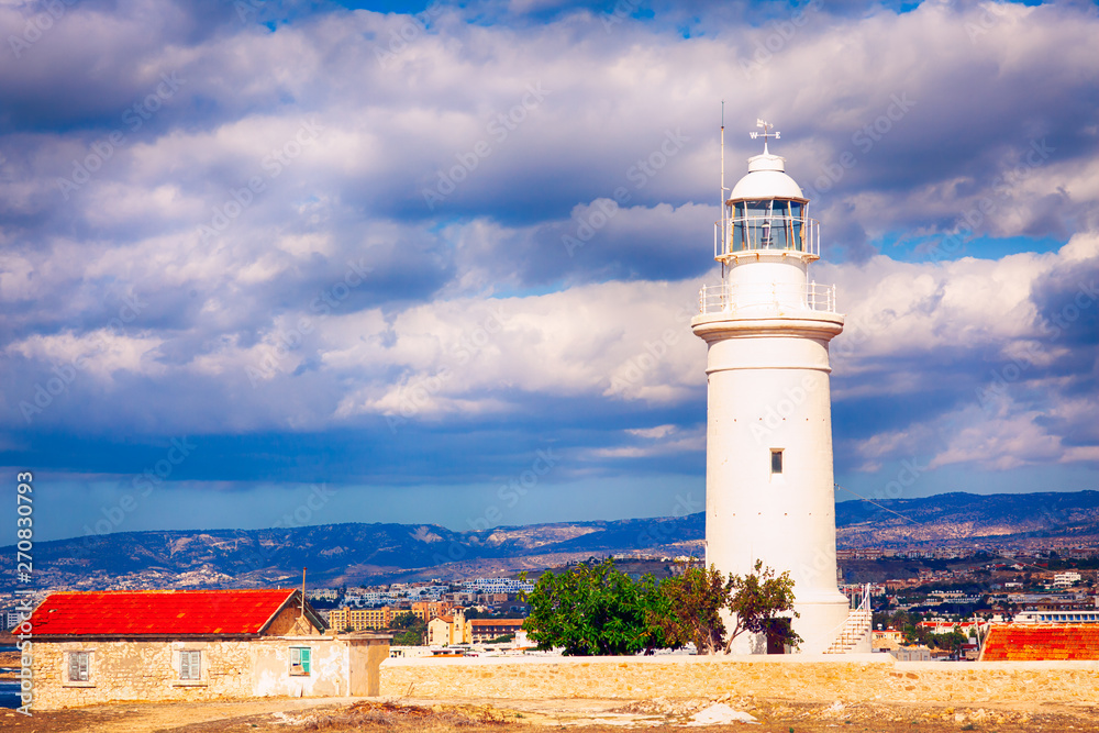 White lighthouse in Paphos Archaeological Park Cyprus against cloudy sky.