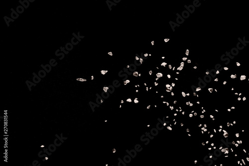Split debris of stone exploding against black background.
