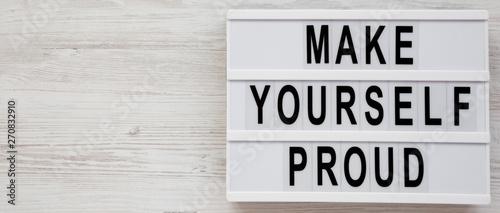 'Make yourself proud' words on a modern board on a white wooden background, top view. Flat lay, overhead, from above. Copy space.