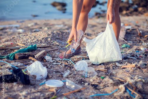 Woman collect garbage on the beach. Environmental pollution concept