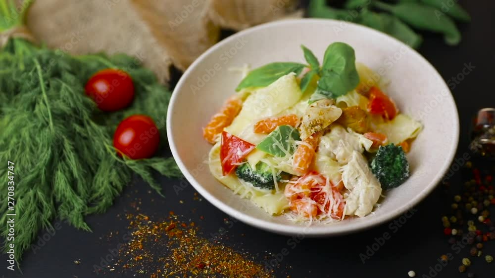 Farfalle pasta with tomatoes, garlic, broccoli, pesto sauce and grated parmesan cheese. Slow-mo Farfalle pasta with tomatoes, garlic, broccoli, pesto sauce and grated parmesan cheese. Slow-mo