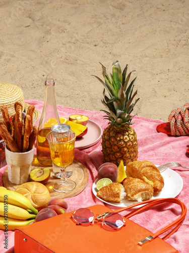 Picnic on the sandy beach. Fruit, drinks and beach accessories on a pink blanket. photo