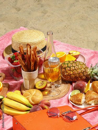 Picnic on the sandy beach. Fruit, drinks and beach accessories on a pink blanket. photo