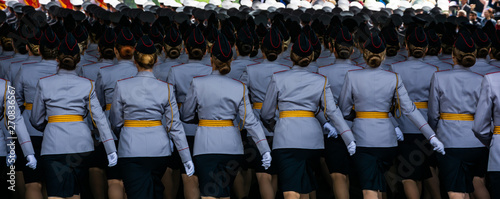 Military women in colorful uniform gracefully marching during victory day parade, back view, panoramic crop.