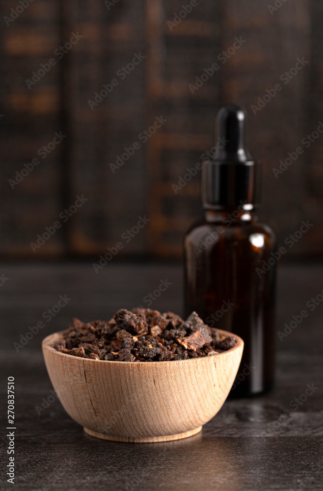 Bowl of Myrrh on a Dark Wood Table with a Bottle of Essential Oil Bowl of Myrrh on a Dark Wood Table with a Bottle of Essential Oil