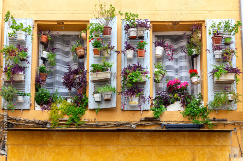 Aix-en-Provence. Window in the orange facade of the old house decorated with flowers.