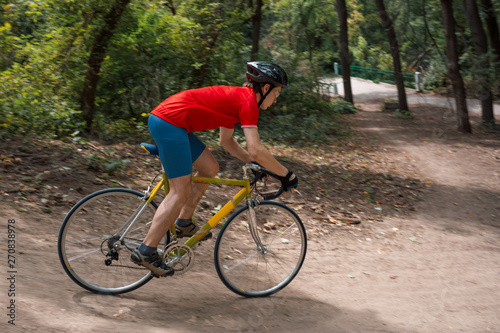 A cyclist rides on a road bicycle, coming down hill.