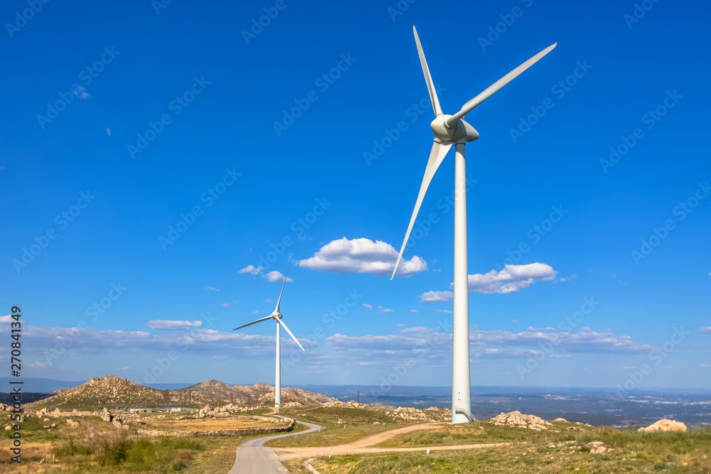 View of a mountains landscape with road and wind turbines on top
