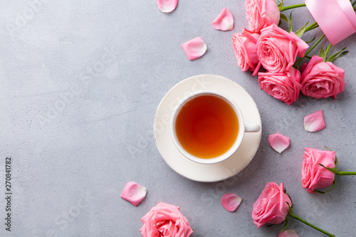 Cup of tea with pink rose. Top view. Copy space. Grey stone background.