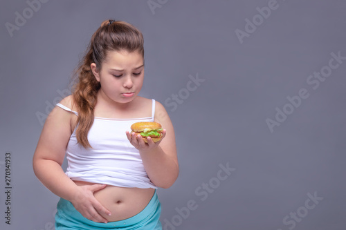healthy eating, glutton, bad nutritional habits, overeating, fast food, overweight. baby girl with excess weight keeps the stomach.  copyspace