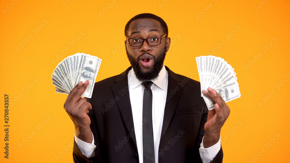 Successful african businessman in eyeglasses showing bunches of cash, profit Successful african businessman in eyeglasses showing bunches of cash, profit