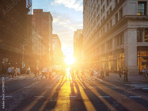 View of a busy intersection in Manhattan with sunlight shining on crowds of people in New York City © deberarr