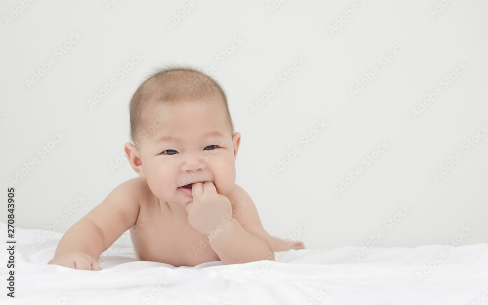 portrait of little small asian baby infant relaxing after bath looking to the right side with his finger in mouth portrait of little small asian baby infant relaxing after bath looking to the right side with his finger in mouth