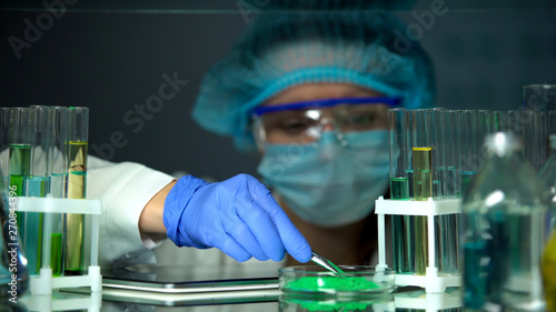 Laboratory worker taking green powder sample from petri dish, experiments photo