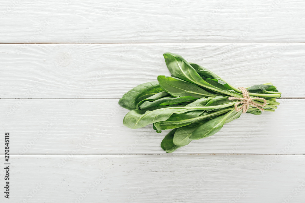 top view of green spinach leaves on white wooden table top view of green spinach leaves on white wooden table