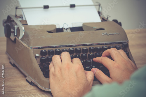 BANGKOK, THAILAND - April 1, 2017: Hands writing on Vintage Olympia Manual Typewriter on wooden desk.