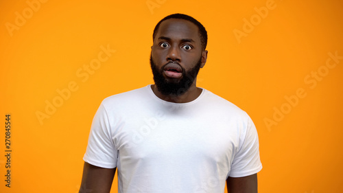 Vászonkép Shocked African-American man looking at camera isolated on yellow background