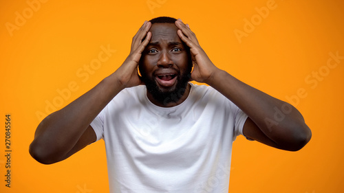 Shocked African-American man holding head, life problems, bad news, gossips