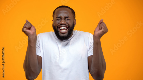 Young Afro-American man feeling happiness, lottery winner, yellow background