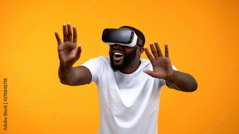 Naklejka premium Happy African-American man using VR headset exploring future technologies