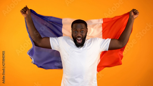 Obraz na plátně Excited black man holding French flag, supporting national sports team, cheering