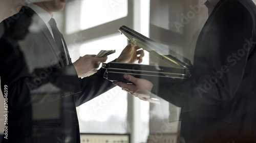 Lawyer opening case and looking at money, concept of illegal job offer, bribe photo