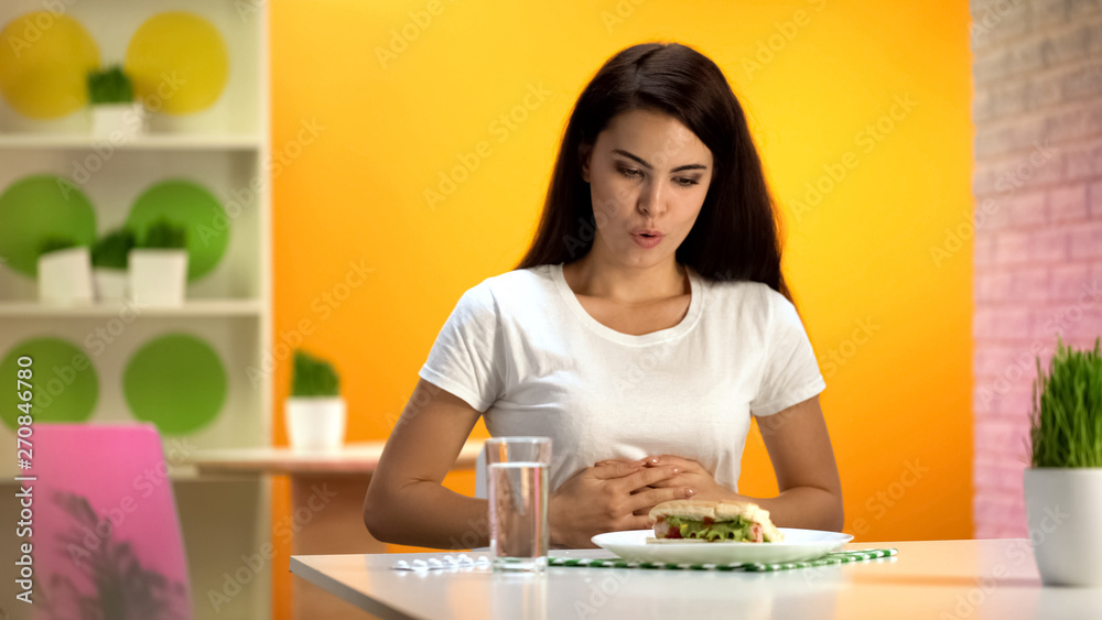 Woman touching stomach after high-calorie meal, overeating problem, gastritis Woman touching stomach after high-calorie meal, overeating problem, gastritis